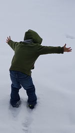 Rear view of boy playing on snow covered field