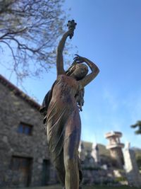 Low angle view of statue against building against sky