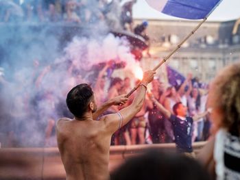 Rear view of shirtless man waving flag at music festival