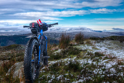 Blue bicycle on mountains against cloudy sky at dusk