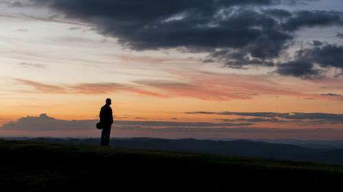 Silhouette man standing on land against sky during sunset