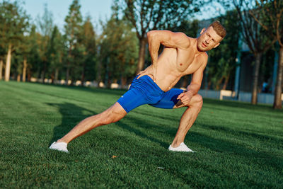 Full length of shirtless man running on grass
