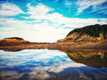 Reflection of rocks in sea against sky