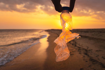 Volunteer woman collecting plastic holey bottle for beach cleanup, women cleaning up trash, ecology