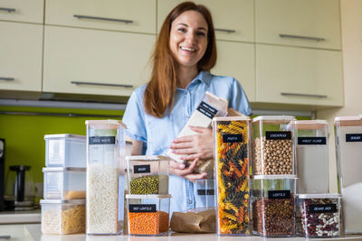 Portrait of smiling woman holding spices at kitchen