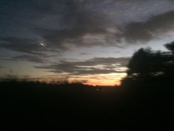 Silhouette trees against dramatic sky during sunset