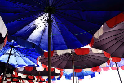 Low angle view of umbrellas hanging against blue sky