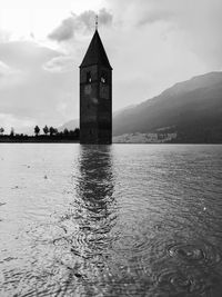 Building by sea against cloudy sky