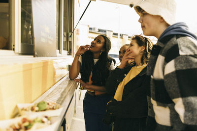 Male and female friends choosing food from menu while standing near concession stand