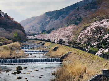 Bridge over river by mountains against sky