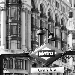 Metro sign against buildings in city