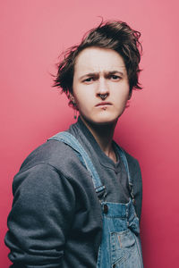 Trendy young man looking suspiciously over pink background