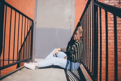 Thoughtful young woman sitting in balcony during sunny day