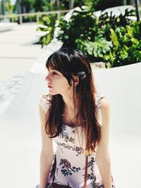 Young woman looking away while sitting outdoors