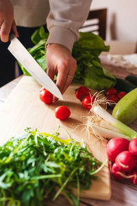 Cropped hand of man holding vegetables on cutting board