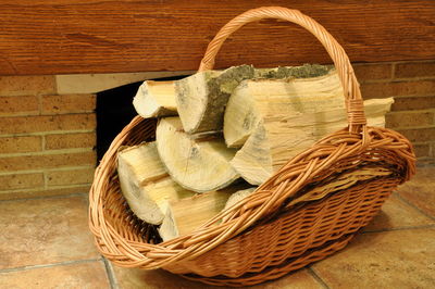 Firewood in a wicker basket in front of the fireplace