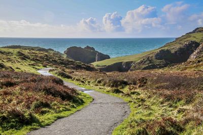 Scenic view of road by sea against sky