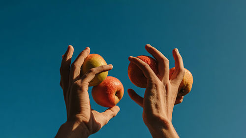 Low angle view of hand against clear blue sky