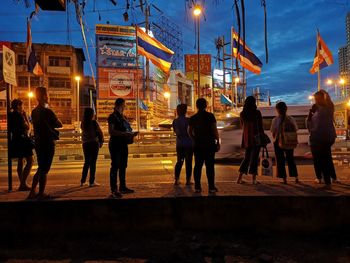 People walking on illuminated street at night