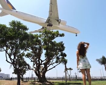 Woman standing by tree against sky