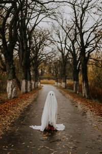 Little ghost standing on the road in red boots. autumn halloween