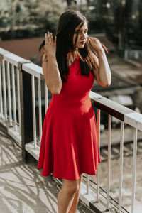 Young woman looking away while standing by railing