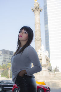 Low angle view of woman standing against statue in city