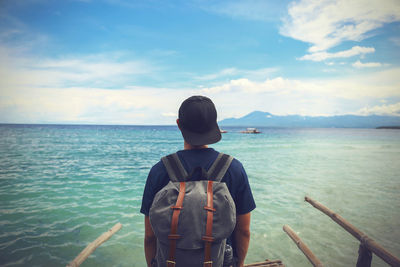 Rear view of man with backpack looking at sea against sky