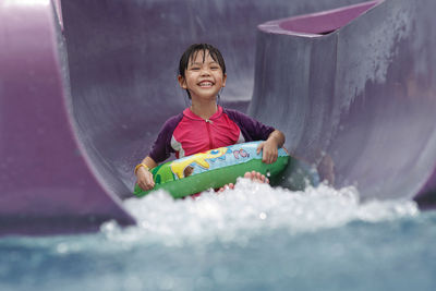 Portrait of girl sliding down in water slide at water park