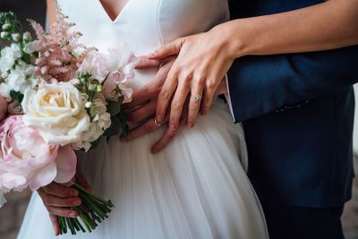 Midsection of bridegroom holding bouquet