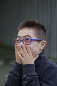 Close-up of happy teenage boy with hands covering mouth