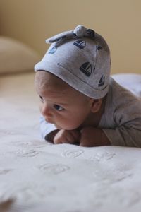 Cute baby boy lying on bed at home