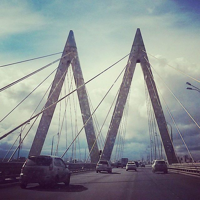 transportation, bridge - man made structure, car, mode of transport, sky, connection, built structure, engineering, architecture, land vehicle, suspension bridge, road, cloud - sky, travel, city, the way forward, cable-stayed bridge, bridge, diminishing perspective, highway