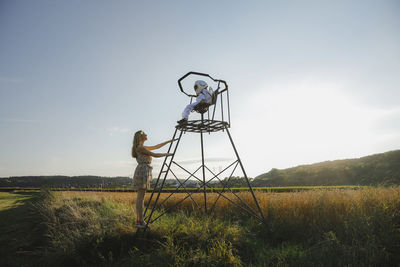 Mother looking at son while standing on lookout tower during sunset