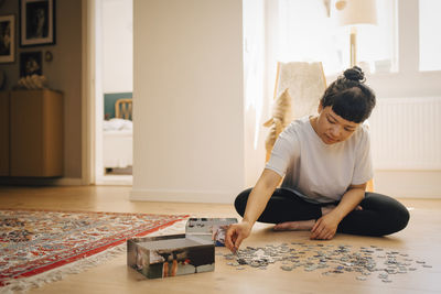 Young woman playing jigsaw puzzle at home
