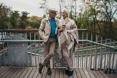 Full length of friends standing on footbridge