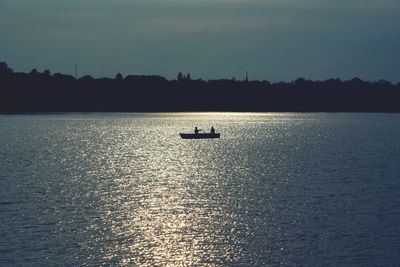 Silhouette boat sailing on sea against sky during sunset