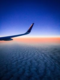 Airplane wing against sky during sunset