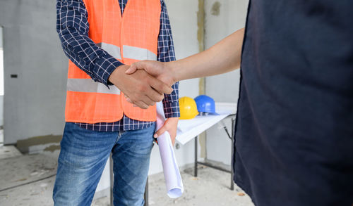 Midsection of engineer shaking hands at construction site