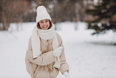 Portrait of young woman standing on snow covered field