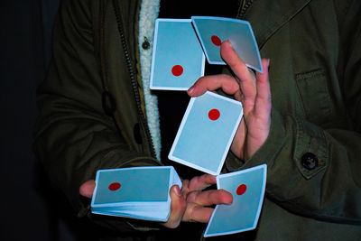 Midsection of illusionist holding cards