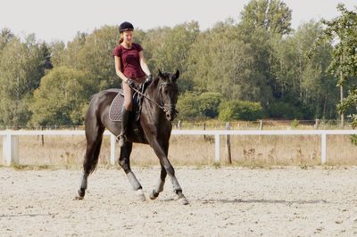 Young woman riding horse on field against sky