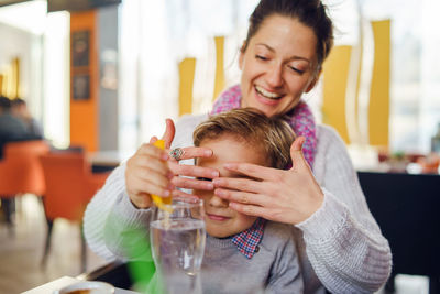 Cute boy and mother sitting on table