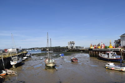 Boats moored at harbor against blue sky