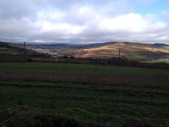 Scenic view of field against cloudy sky