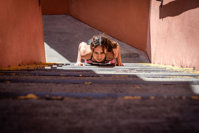 High angle view of young woman focused doing push-ups in staircase outdoors