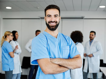 Portrait of smiling doctor with colleagues discussing in background