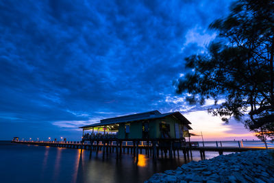 Building by trees against blue sky at dusk