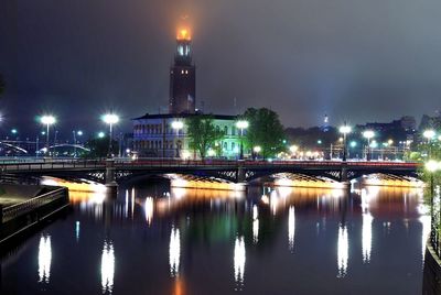 Illuminated bridge over river in city at night