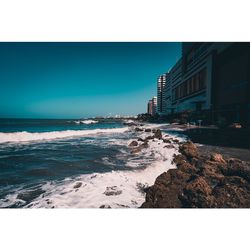 Scenic view of sea against buildings against clear sky